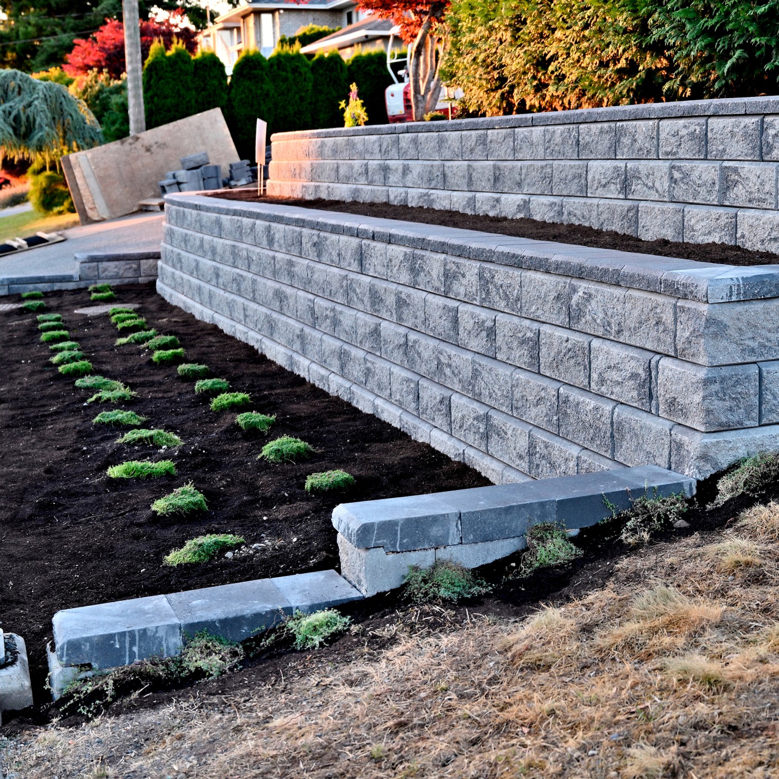 Newly constructed concrete block retaining wall with fresh soil and planted greenery by Willamette Valley Landscape in Salem, Oregon.